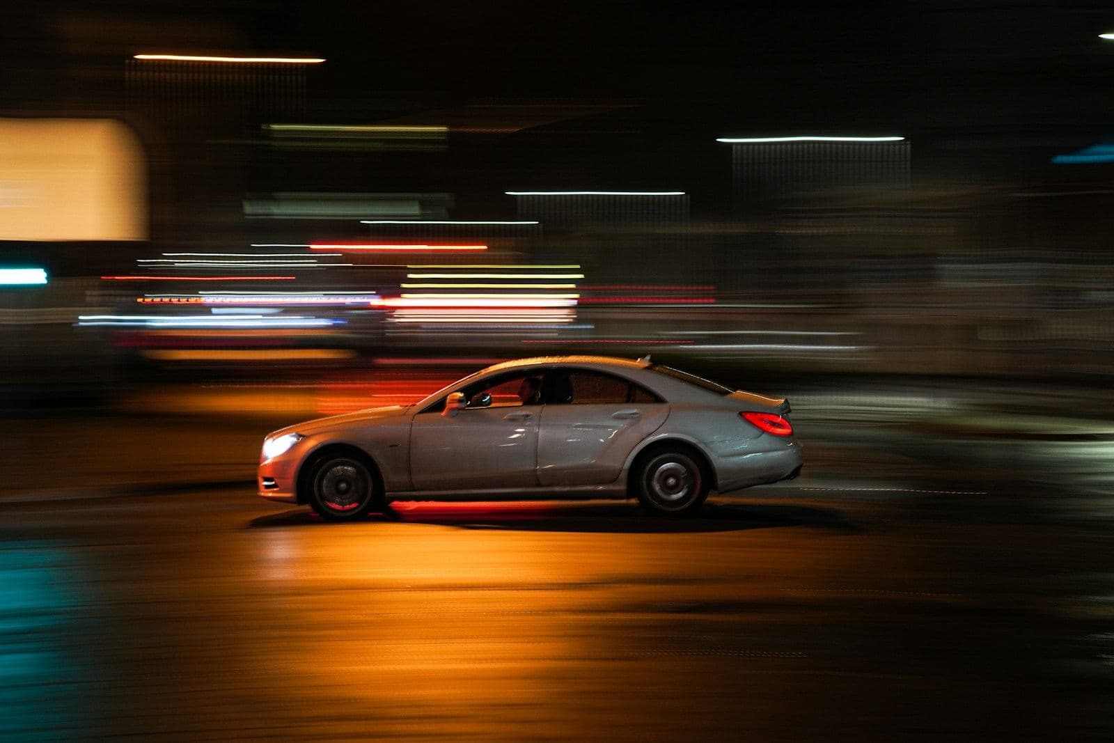 A black chauffeured sedan moving through the city after dark